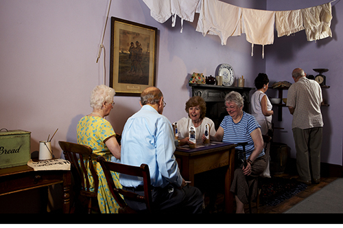 Four people sit around a table in a reconstructed Victorian room at the People's History Museum.