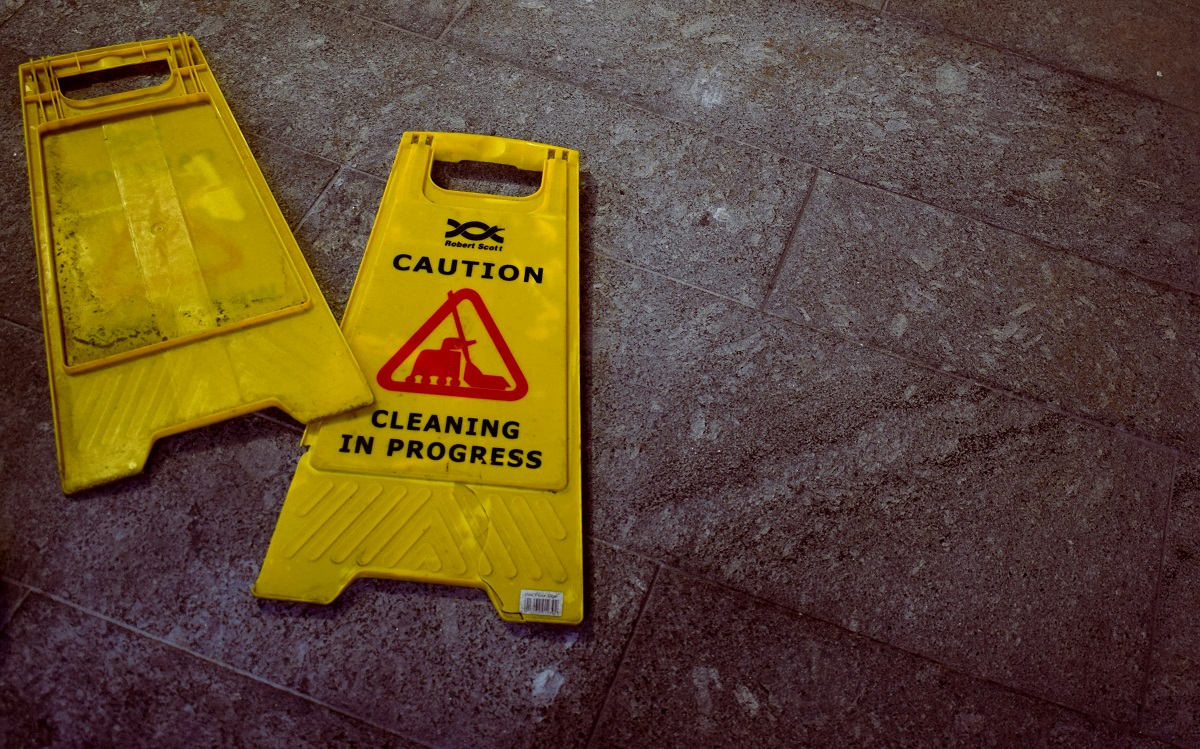 Two yellow caution signs lying flat on a grey floor