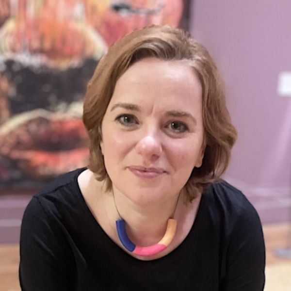 A woman smiling. There is an artwork in the background.